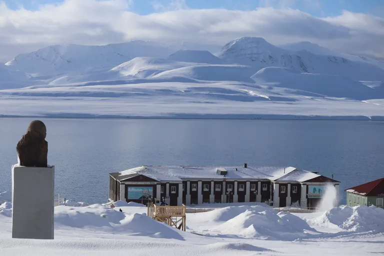 スバールバル諸島のバレンツブルグにあるレーニン像と港や雪山の背景