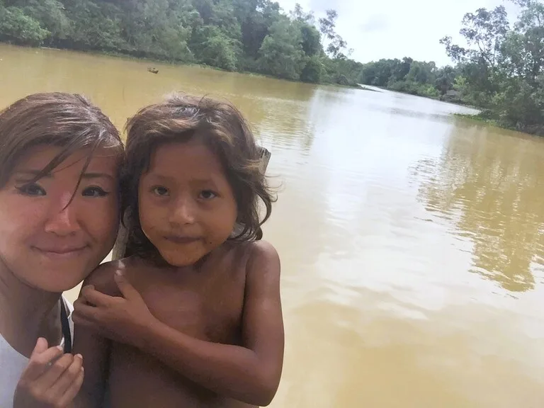 アマゾン川を背景にワラオ族の子どもと記念撮影する観光客