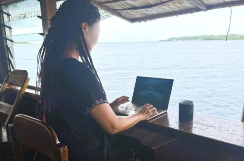 海辺のカウンターに座りVPNを経由してノートパソコンを見ている女の人