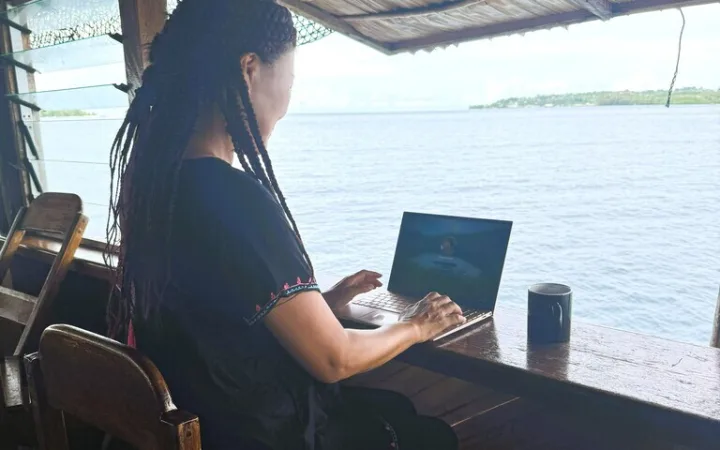 海辺のカウンターに座りVPNを経由してノートパソコンを見ている女の人