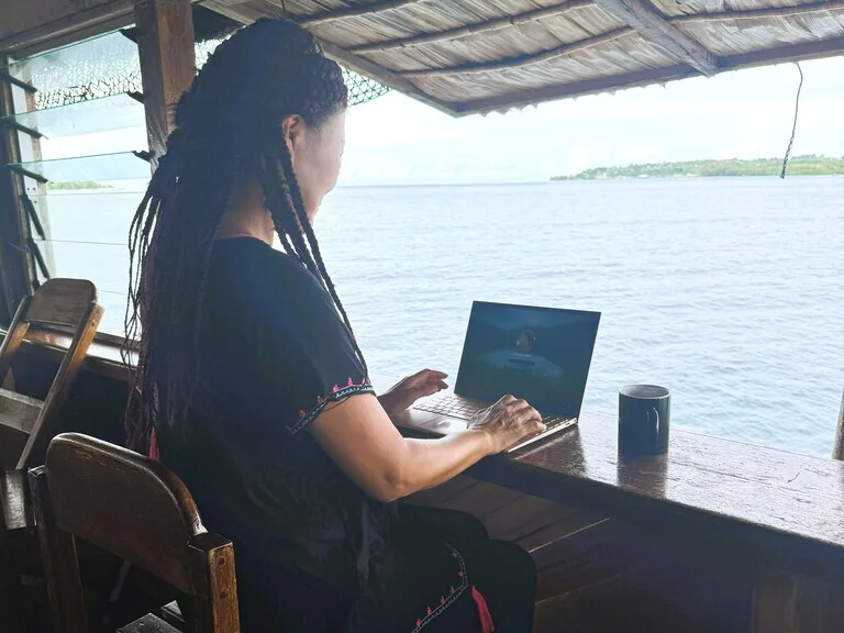 海辺のカウンターに座りVPNを経由してノートパソコンを見ている女の人