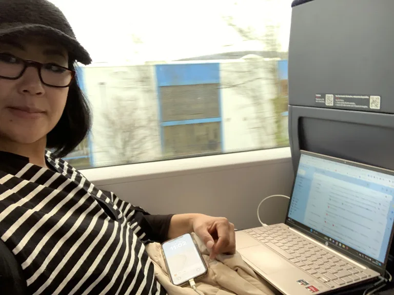 電車の中でVPNをいれたノートパソコンで仕事をしている女の人