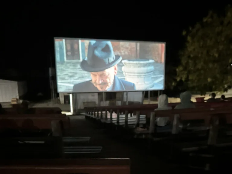 クリスマス島の野外映画館で映画を楽しむ人々と光るスクリーン