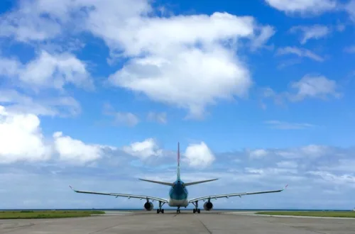 青空の下、滑走路で離陸準備をする飛行機の後方ビュー
