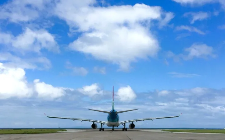 青空の下、滑走路で離陸準備をする飛行機の後方ビュー