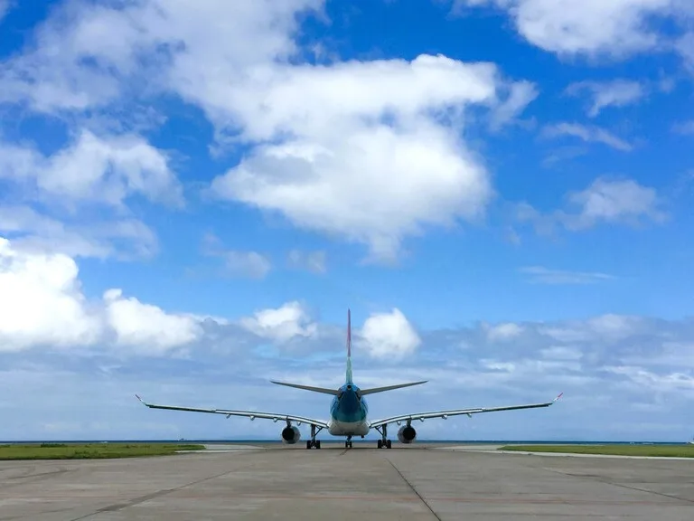 青空の下、滑走路で離陸準備をする飛行機の後方ビュー