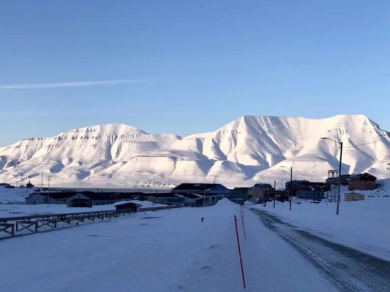 北極圏ロングイェールビーン(Longyearbyen)の町中心へ向かう道と奥に雪山が広がる風景