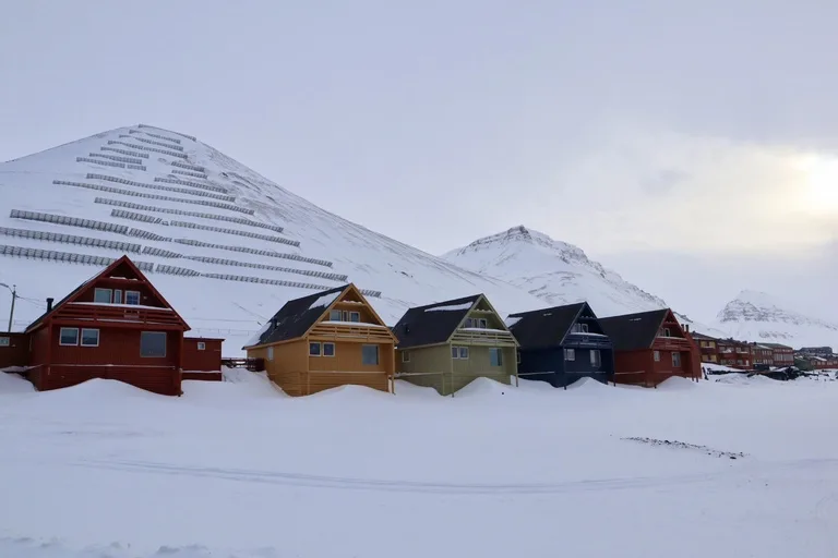北極圏ロングイェールビーン(Longyearbyen)の市街地。色とりどりの家並みと背後に雪山が広がる風景