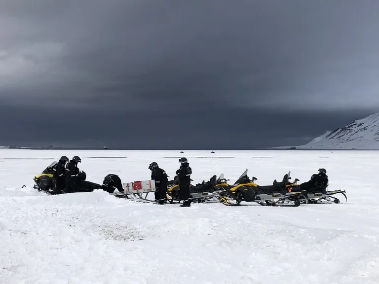 北極圏ロングイェールビーン(Longyearbyen)の雪原の中で佇むスノーモービルのグループ