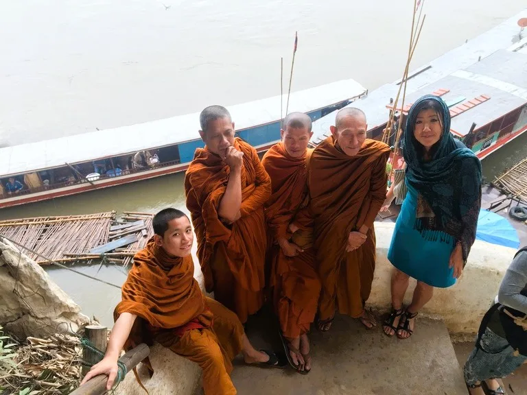 パークウー洞窟(Pak Ou Caves)で僧侶たちと記念撮影する観光客