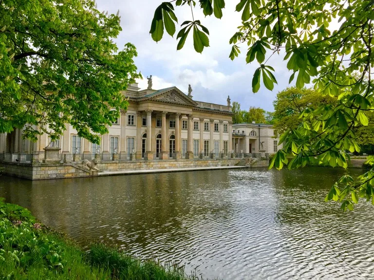 ワルシャワのワジェンキ公園に建つ水上宮殿と、その前に広がる池を囲む緑の風景