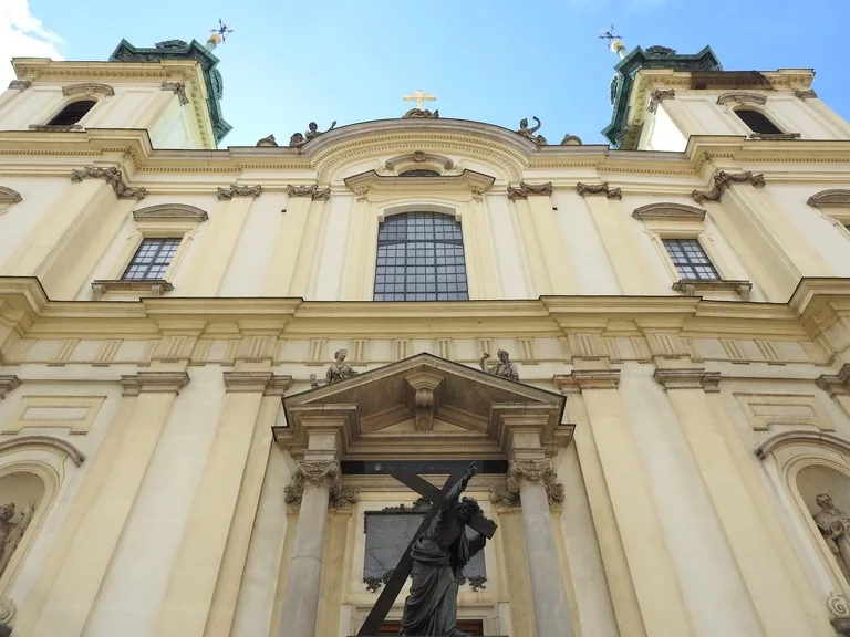 ワルシャワの聖十字架教会(Holy Cross Church)のバロック様式の外観と入口に立つキリスト像