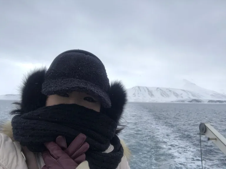 氷山と氷片をバックに自撮りをする北極クルージングの観光客