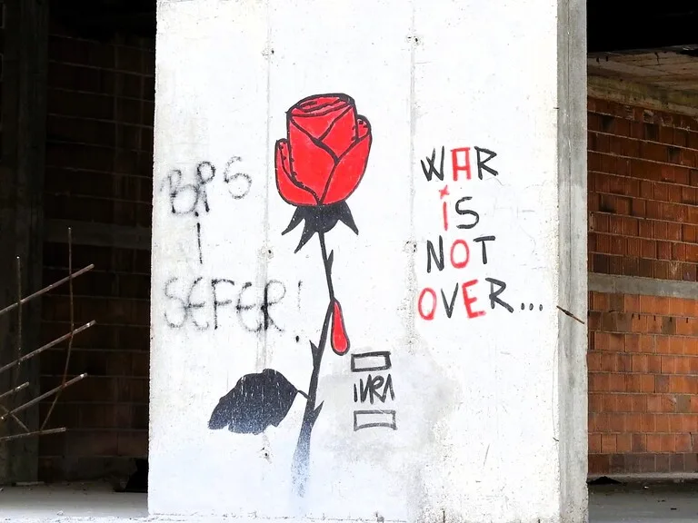 サラエボの壁に架かれたWAR IS BOT OVERの文字とバラの絵