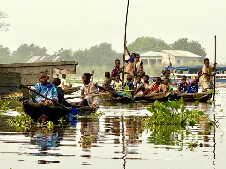 School children commuting by canoe in Ganvié stilt village, Benin