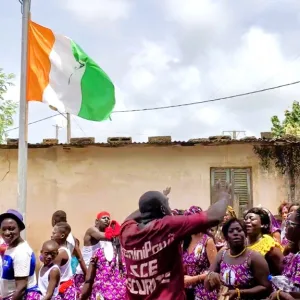 コートジボワールの国旗を掲げ、アフリカンバティック姿で祭りを祝う人々